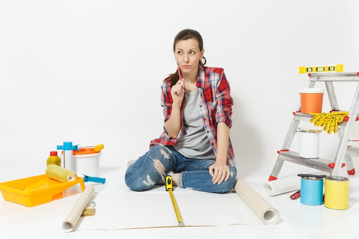 फोटो woman sitting on floor with wallpaper rolls, measure tape, instruments for renovation apartment isolated on white background. accessories for gluing, painting tools. repair home concept. copy space.