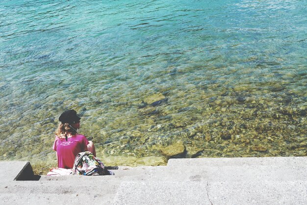 Woman sitting in front of sea during daytime photo