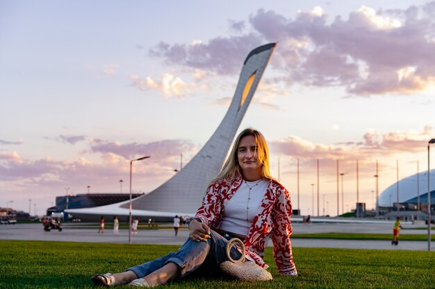 Woman sitting on grass against sochi olympic park facilities