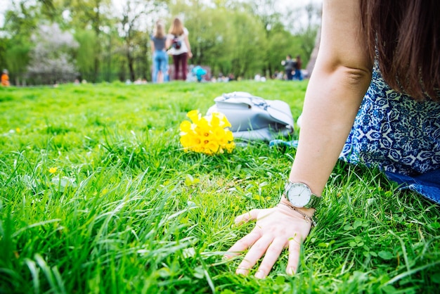 노란 꽃과 함께 도시 공원에서 잔디에 앉아있는 여자