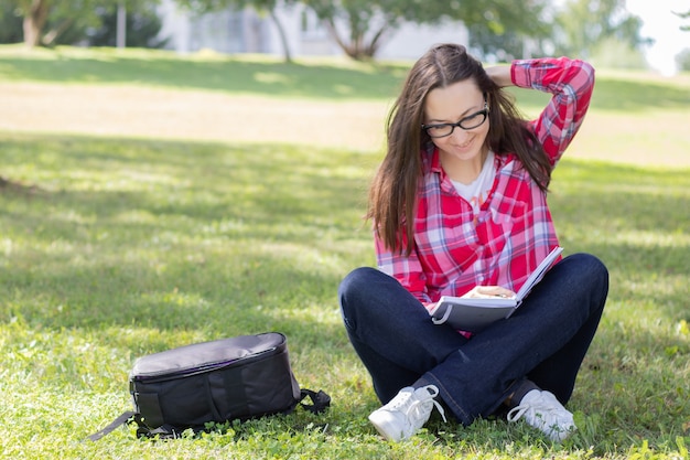 草の上に座って本を読んでいる女性