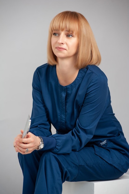 Woman sitting on a grey background Formal dark blue suit Doctor pottrait