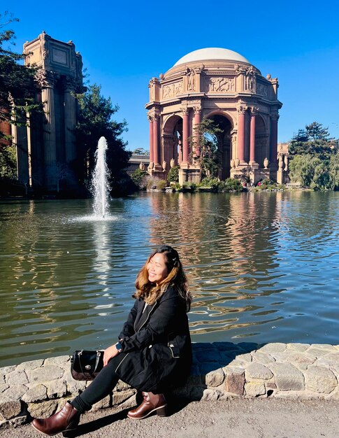 A woman sitting at the grounds of san francisco musuem of fine arts