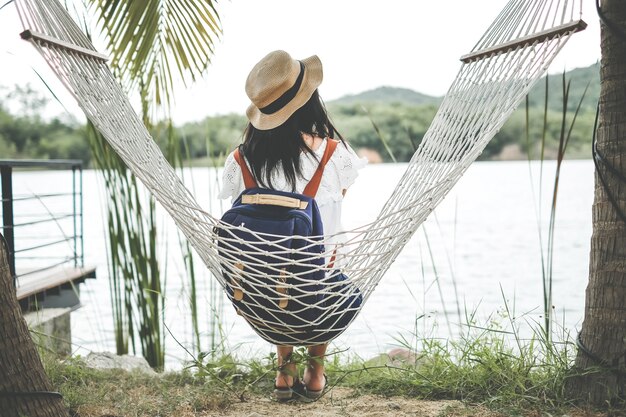 A woman sitting on hammock under coconut tree during holiday. 