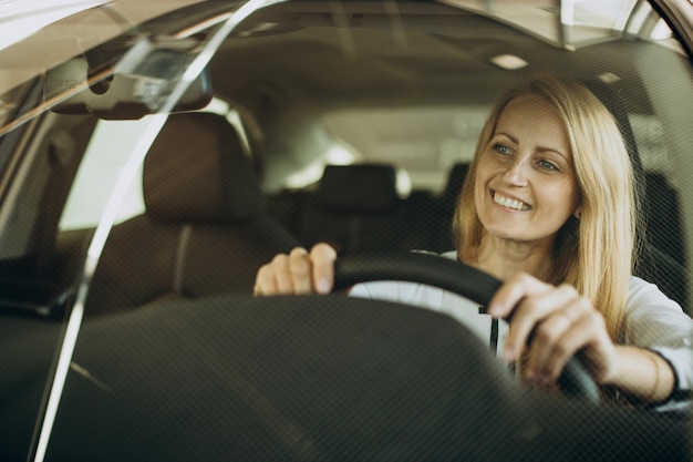 Woman sitting in hee new car in a car salon