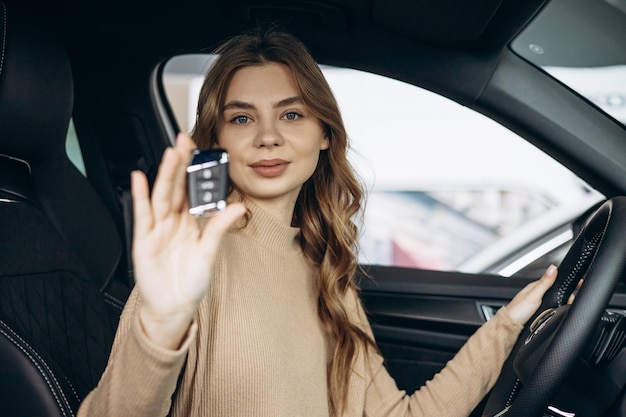 Woman sitting in her new car in car showroom