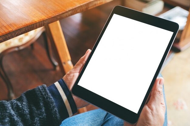 a woman sitting and holding black tablet with blank white desktop screen