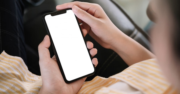 Photo woman sitting and holding blank screen mock up mobile phone