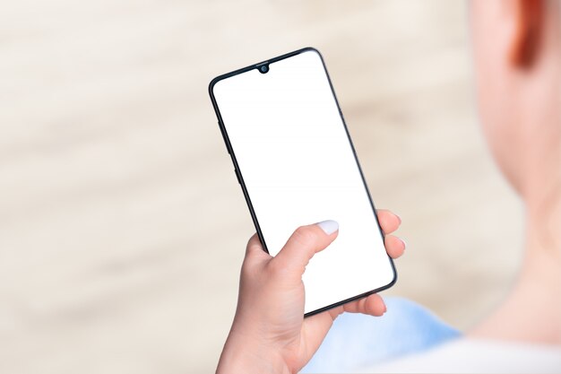 Woman sitting and holding blank screen mock up mobile phone