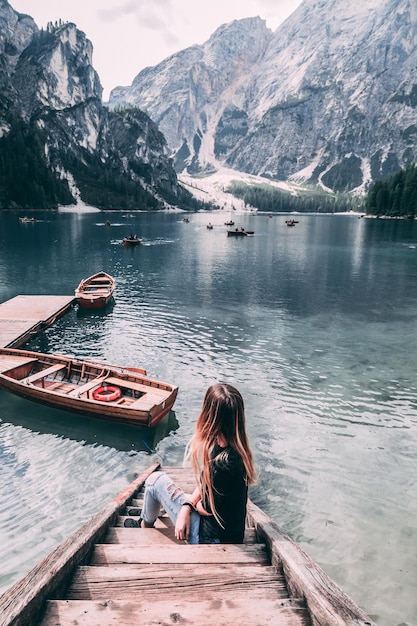 Foto donna seduta sul molo del lago contro le montagne