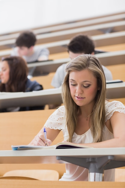 Photo woman sitting in lecture while writing notes