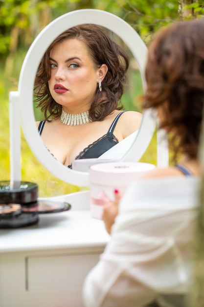 Woman sitting and looking in the mirror in the forest