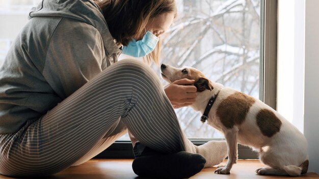 Photo woman sitting in mask at window with a dog