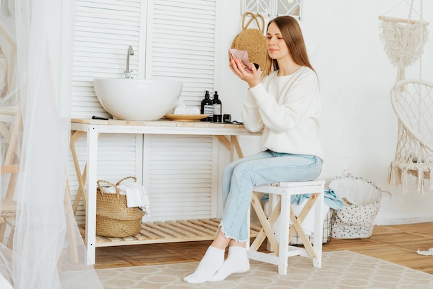 Woman sitting near sink and doing makeup