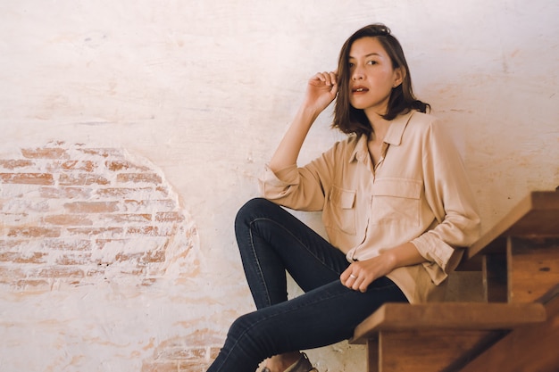 A woman sitting at an old wooden staircase