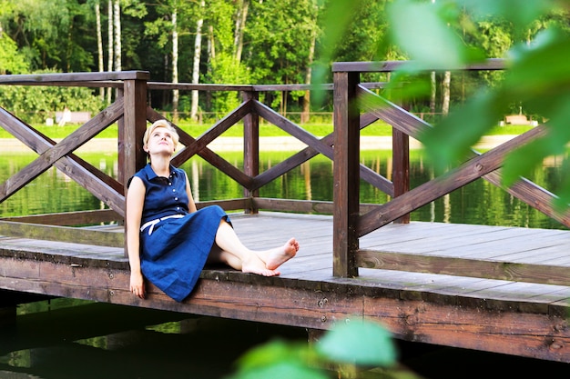 사진 공원에서 물 위에 나무 계선에 앉아있는 여자