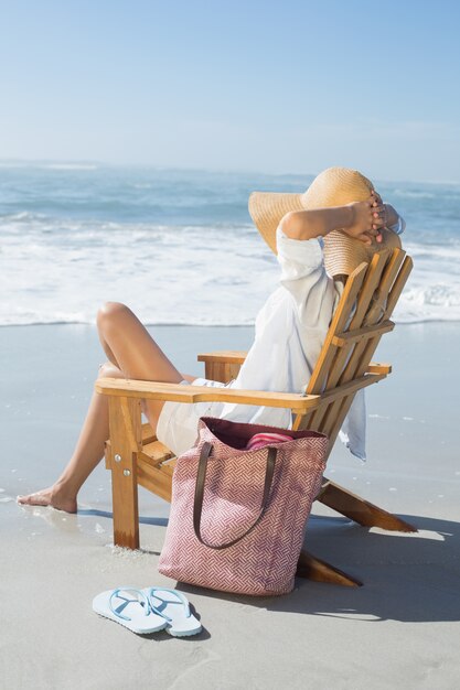 写真 海の木製のデッキチェアに座っている女性