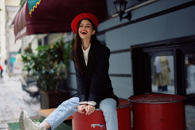 Woman sitting outside a cafe and bar on a city street stylish fashion image of clothes vacation and travel city walk