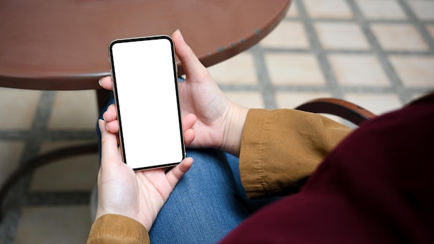 Woman sitting outside of the coffee shop using smartphone chatting with her friends on social media