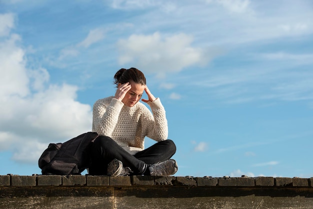 Photo woman sitting outside with her head in her hand looking upset or down