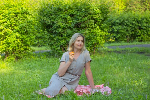 Photo woman sitting in the park in the shade of trees on a sunny day