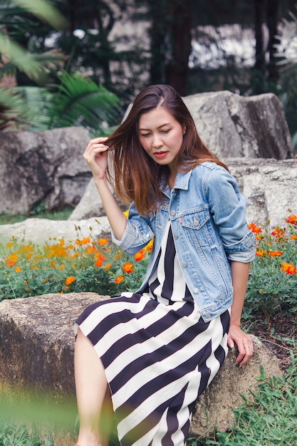 Woman sitting in a park where flowers are blooming beautifully.