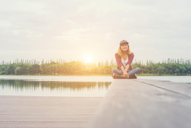 Photo woman sitting on pier over lake during sunset