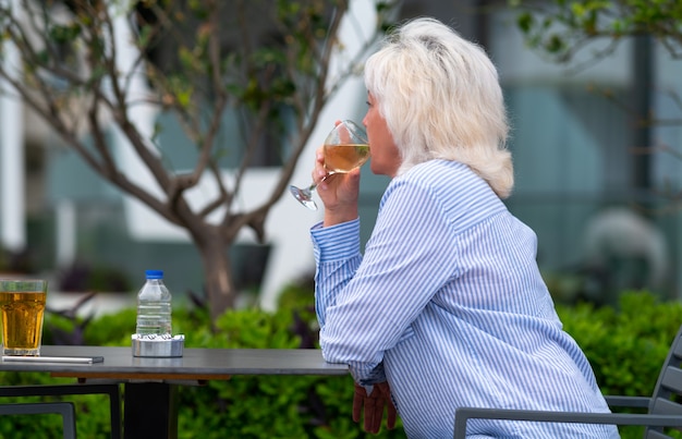 Donna seduta tranquillamente sorseggiando un bicchiere di vino bianco