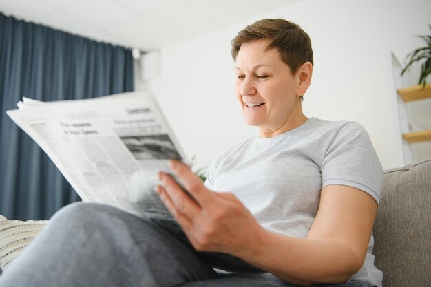 Woman sitting reading the newspaper at home