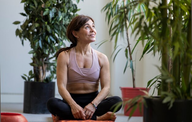 Woman sitting relaxed in a yoga room looking out a window