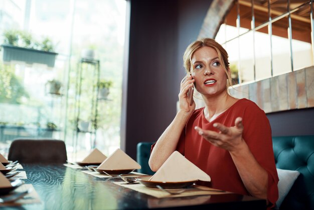 Woman sitting at restaurant and talking on phone