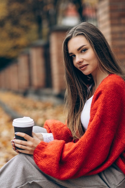 Woman sitting on the road and drinking in autumn season