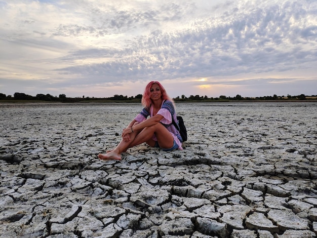 Foto donna seduta su una roccia sulla spiaggia contro il cielo durante il tramonto