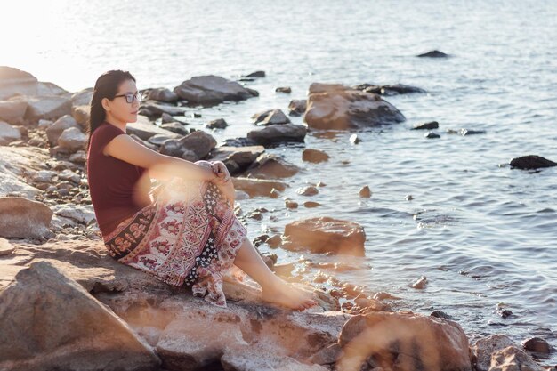 Photo woman sitting on rock at beach