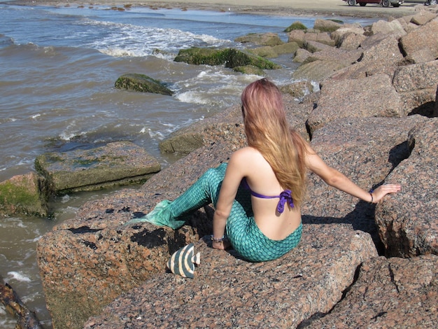 Photo woman sitting on rock by sea