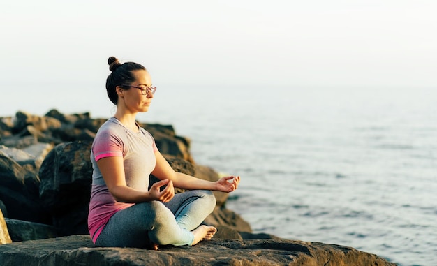 woman sitting on rock by sea