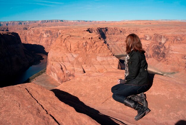 Woman sitting on a rock looking at a view, horseshoe bend, glen
canyon national recreation area, arizona-utah, usa