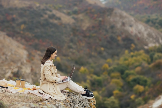 woman sitting on rock and using laptop