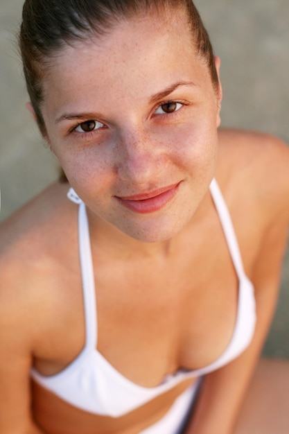 하얀 수영복을 입고 해변에서 모래에 앉아 있는 여자