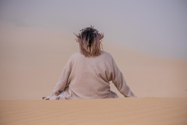 Woman sitting on sand dune