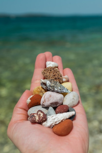 Woman sitting at sea beach playing with rocks