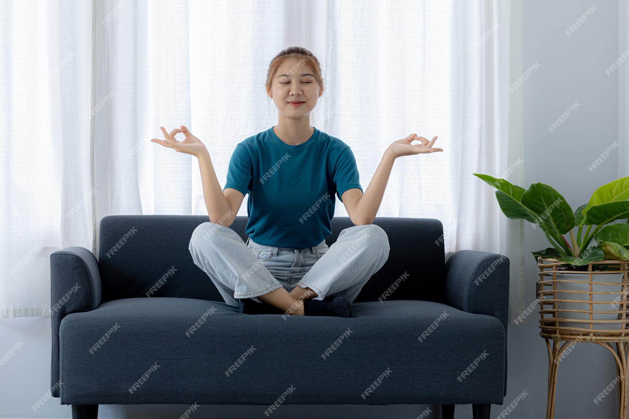 Premium Photo | Woman sitting on sofa doing yoga poses she is relaxing on  the sofa in the living room on vacation she does yoga poses to relax after  a hard day's