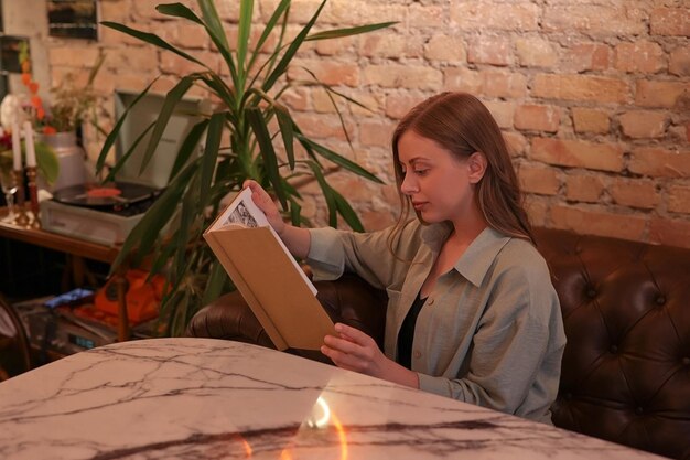 Woman sitting on the sofa in the evening light reading a book