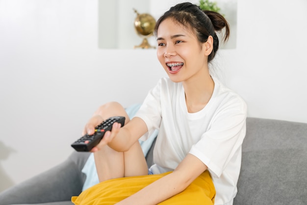 Woman sitting on the sofa and holding the TV remote