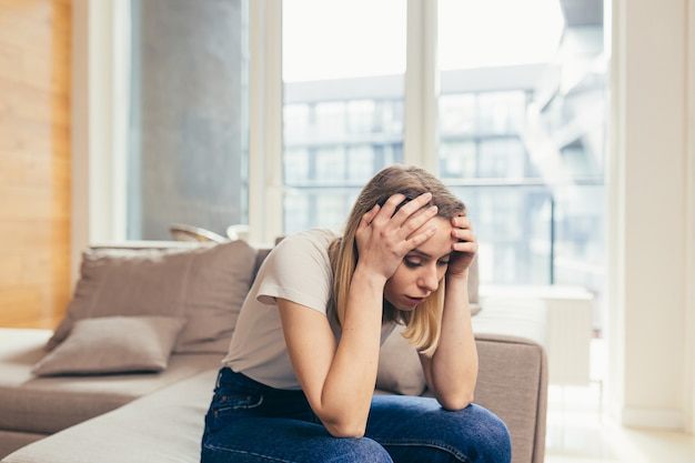 woman sitting on sofa at home depressed