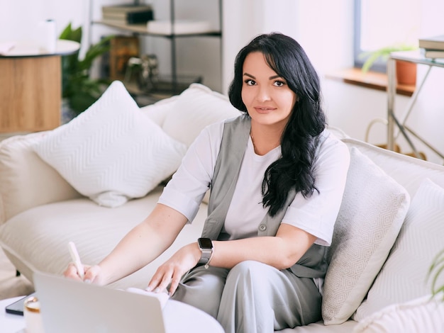 woman sitting on the sofa and making notes in her notebook Business analytics education