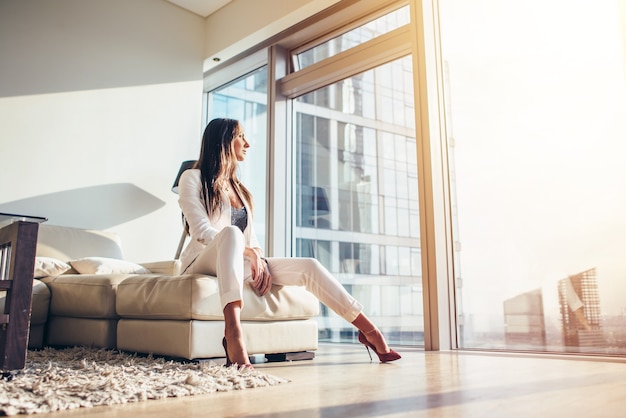 Woman sitting on a sofa at modern apartment.