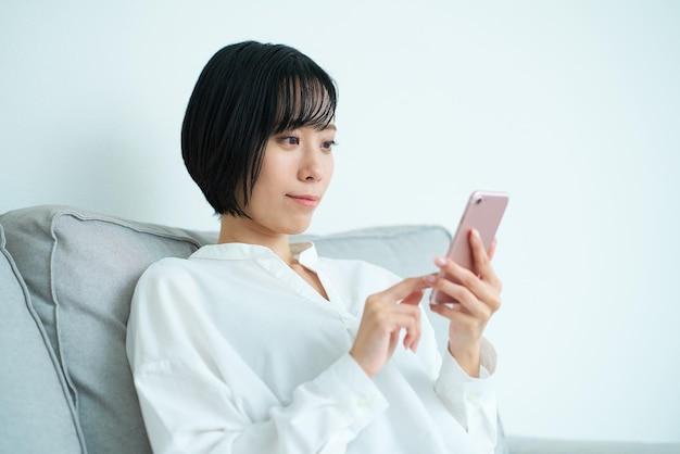 Woman sitting on sofa and using smartphone