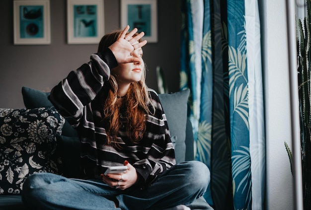 Photo woman sitting on sofa not willing to be photographed