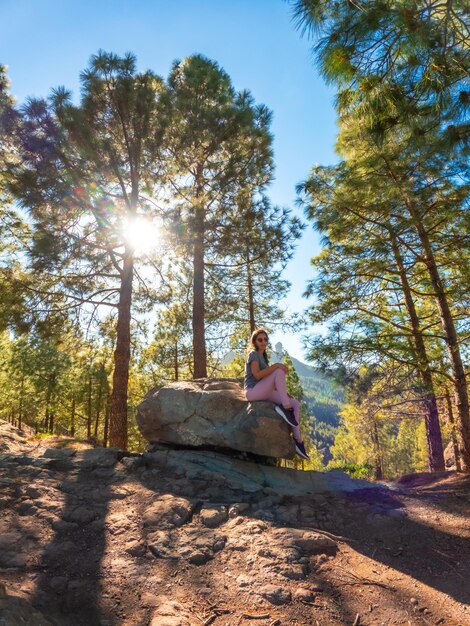 Photo a woman sitting on a stone while hiking to roque nublo in gran canaria canary islands